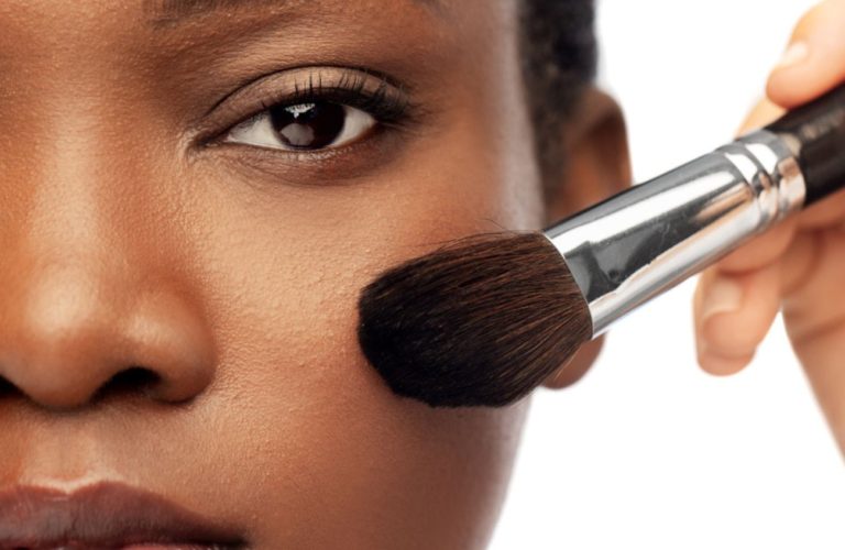 Makeup artist sweeping brush against models face