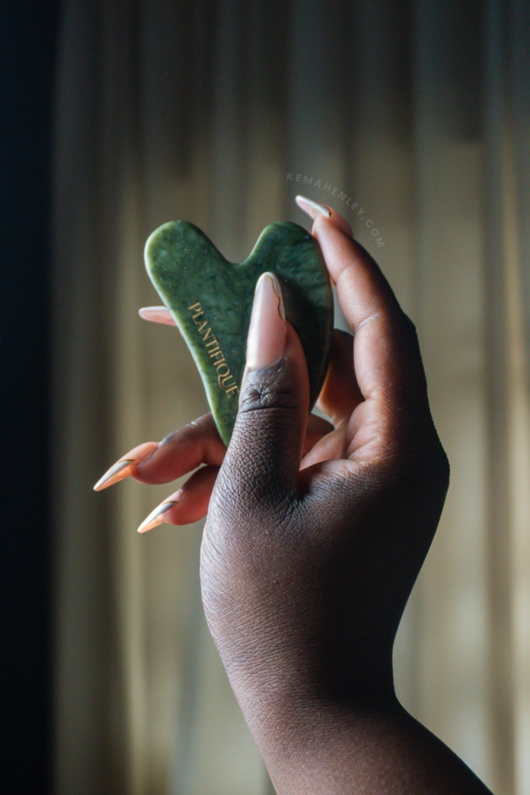 a hand holding a jade Gua Sha