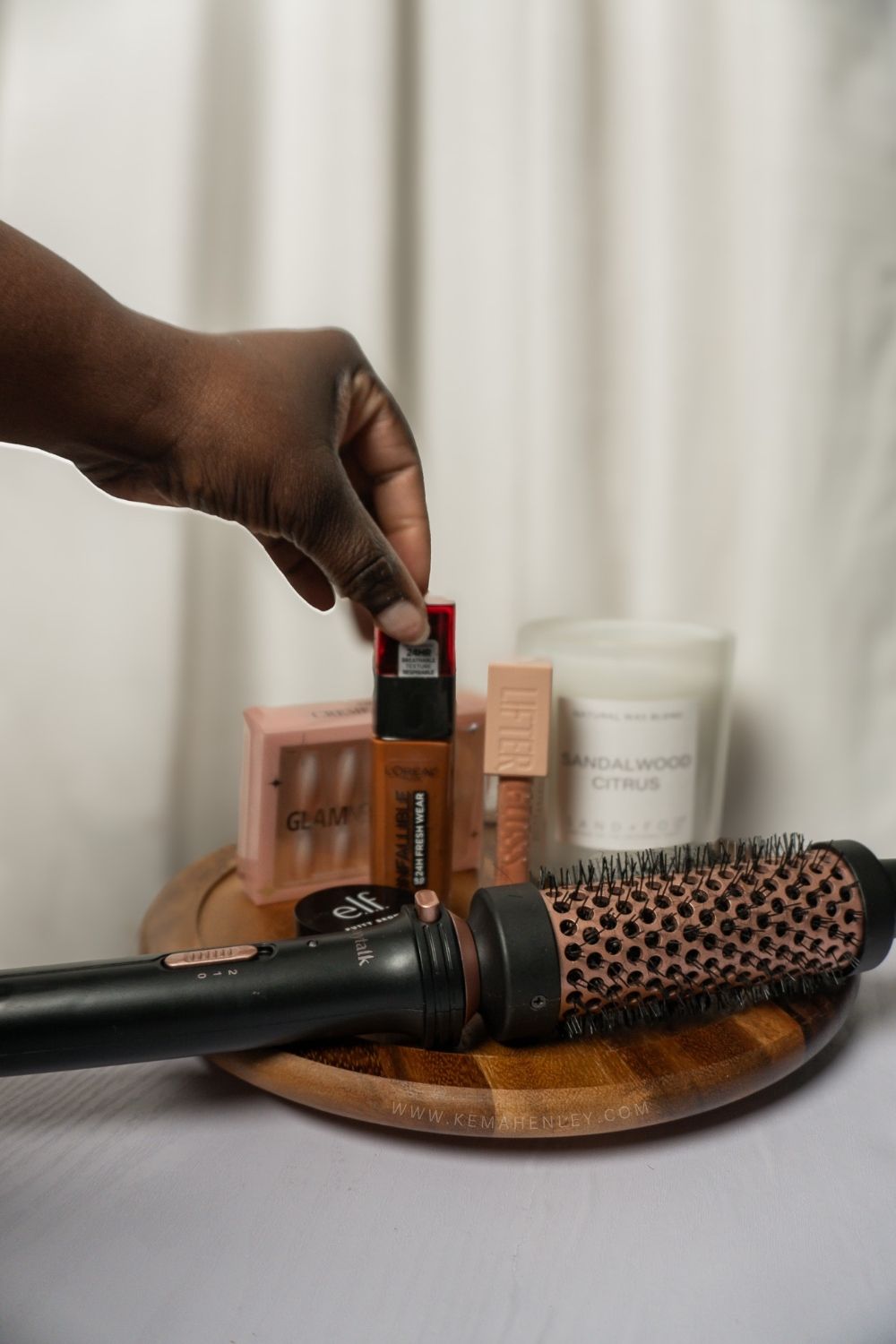 a hand grabbing makeup off a desk